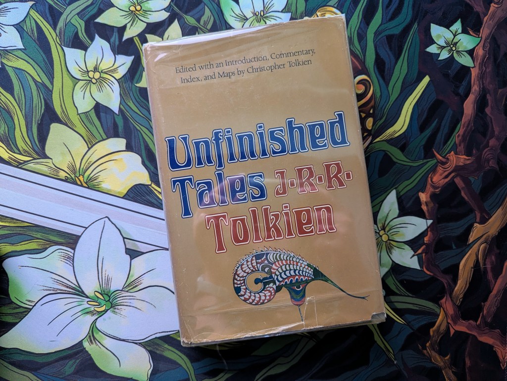 a first US edition of Unfinished Tales sits on a Rohan-themed desk mat