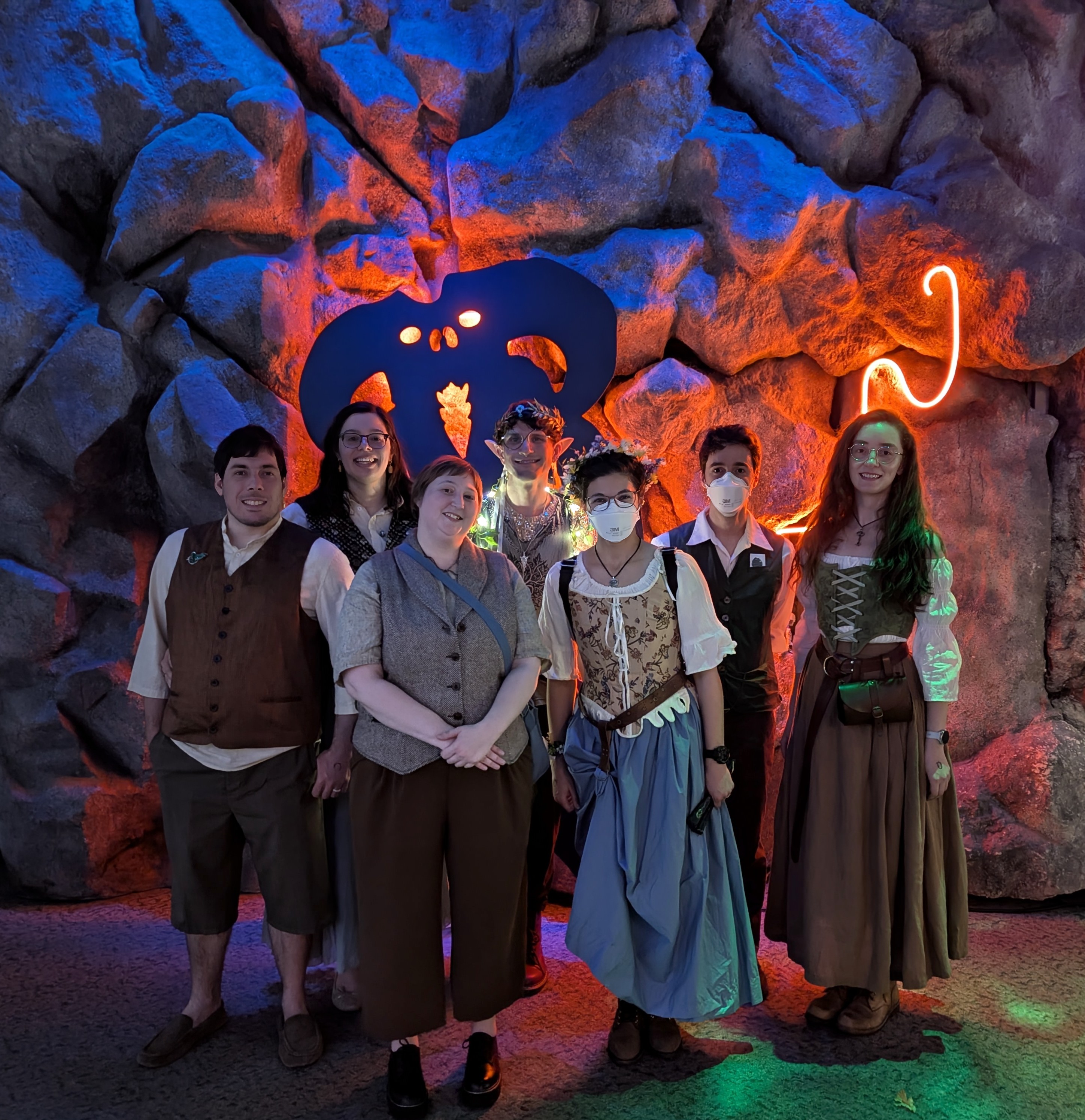 A group of costumed Tolkienists stand together in front of a balrog in a cave